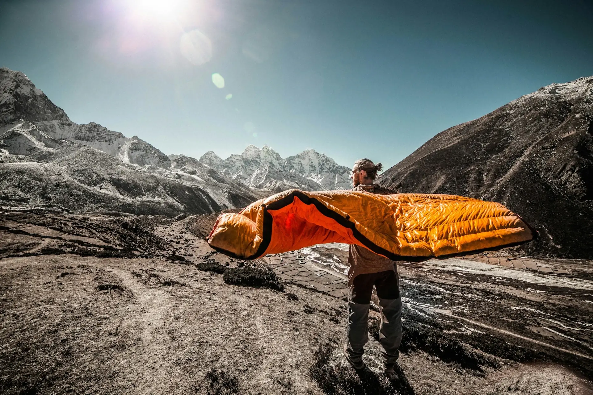 A hiker fluffs out a sleeping bag in the morning light