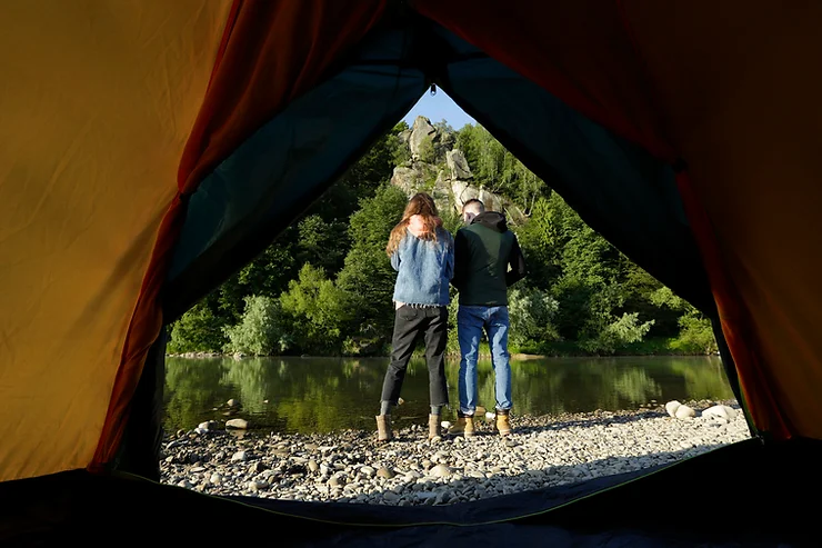 An image of looking out of a tent flap to a view of a lake