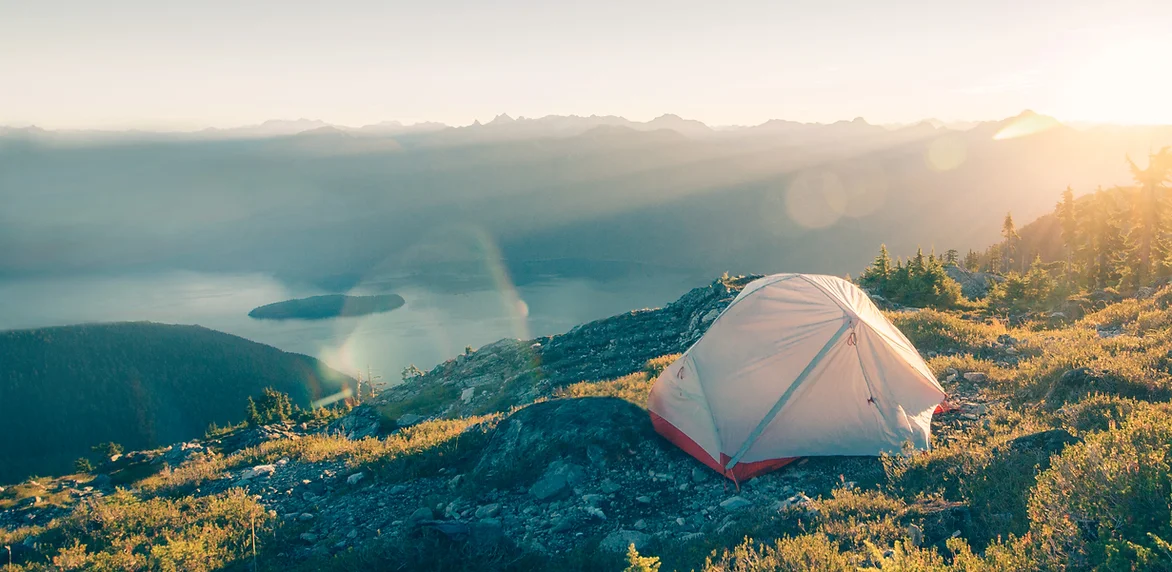 An image of a tent overooking a beautiful hilly ridge at sunset